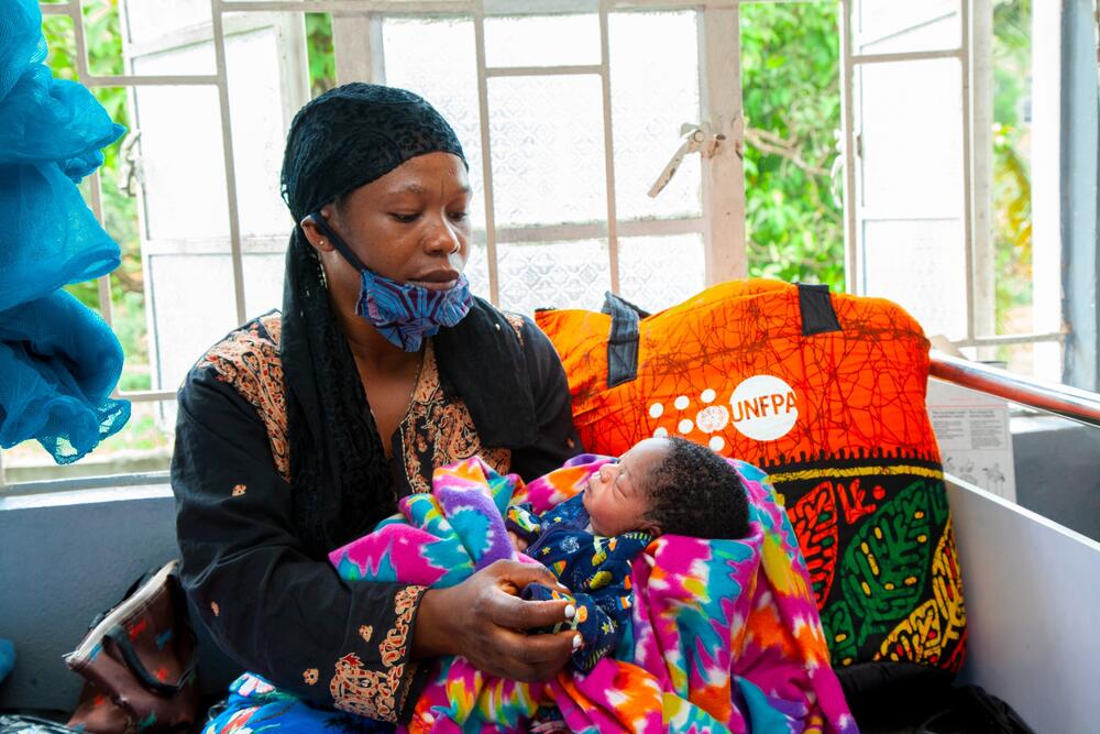 A woman holds an infant in her arms. 